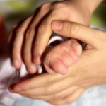 Mother holds baby's hand