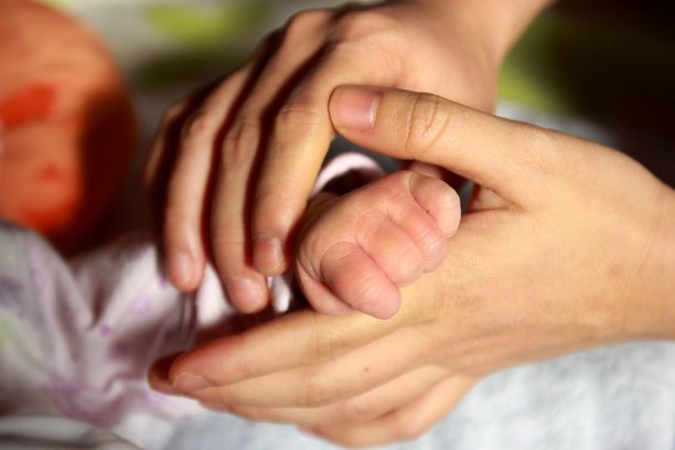 Mother holds baby's hand
